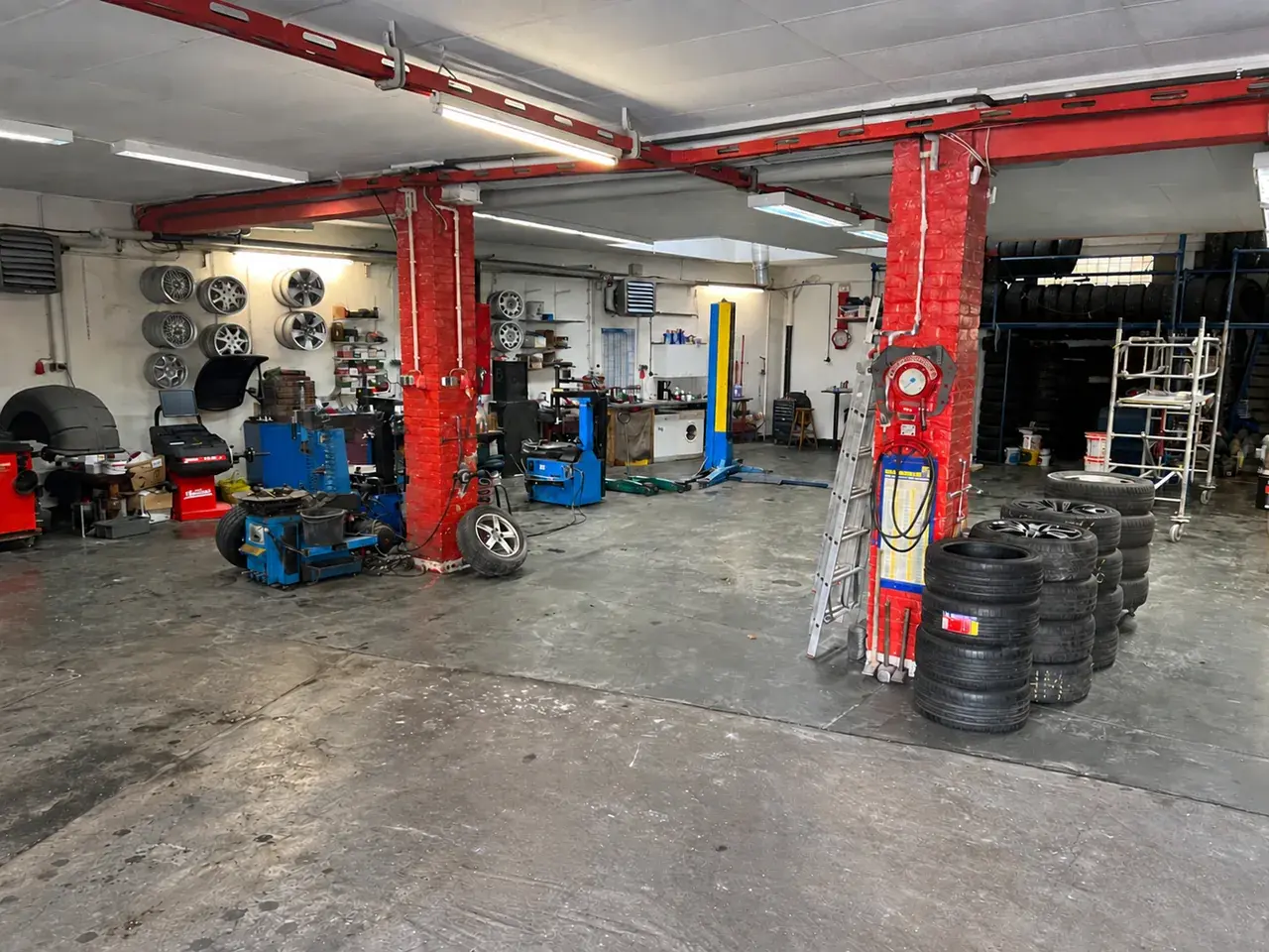 Werkstatthalle mit freier Rampe, roten Stützen und Reifenstapeln